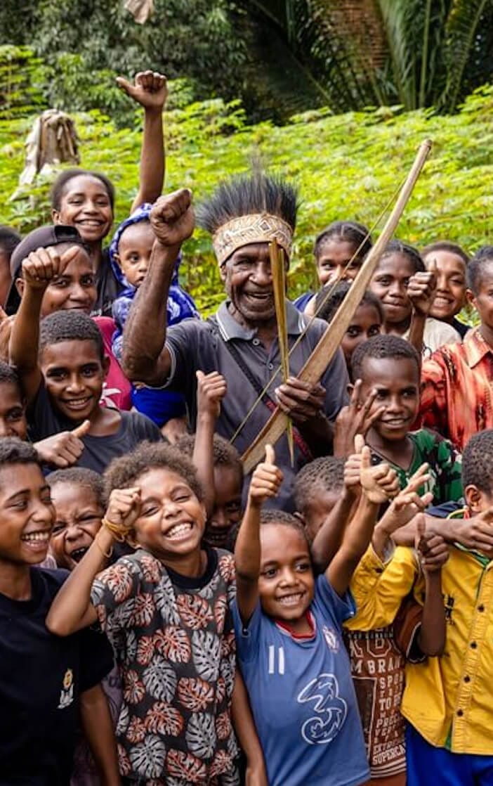 Community members gathering outdoors in a tropical forest landscape