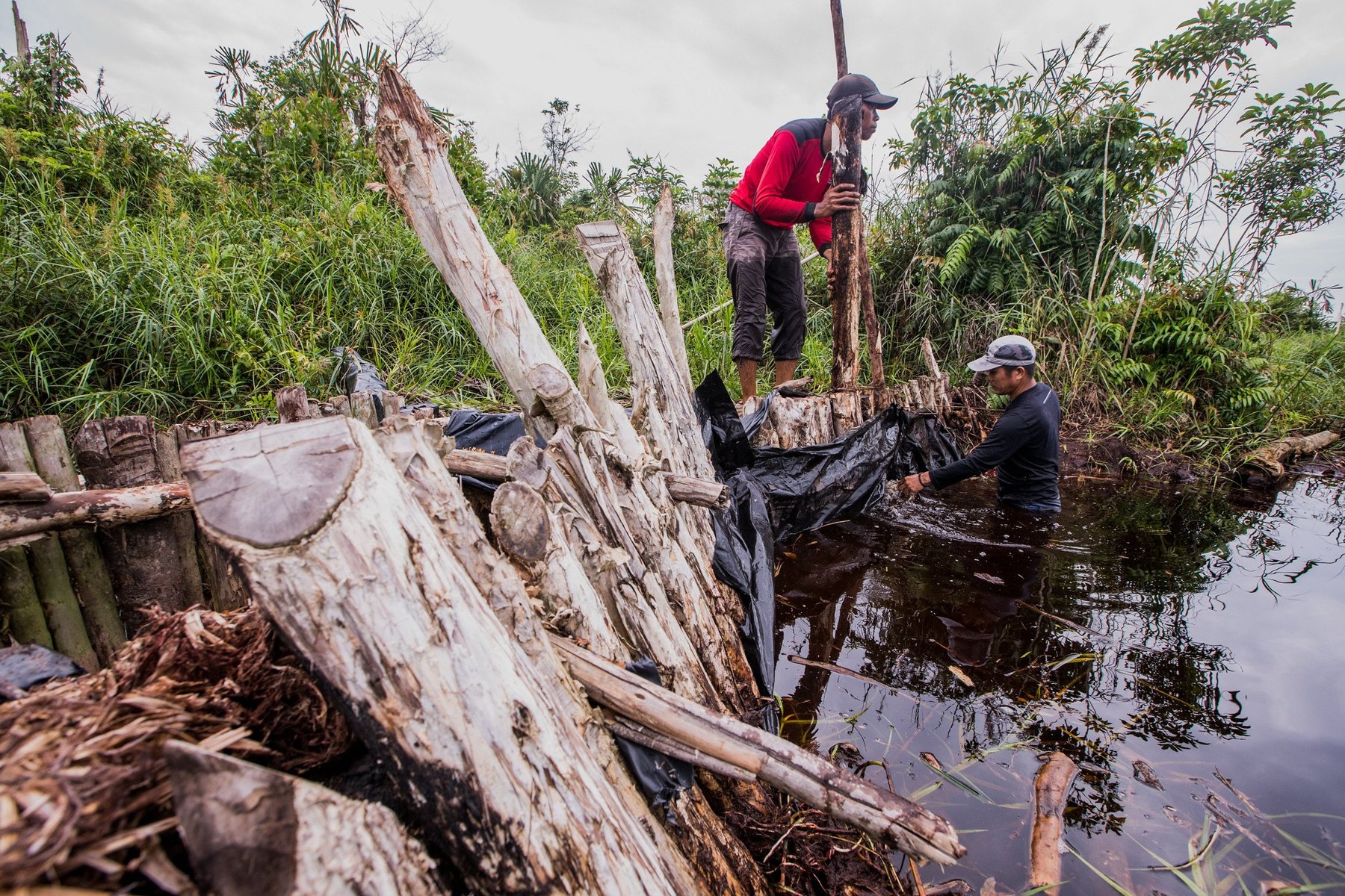 A team building a canal block to hold water back in drained peatland.